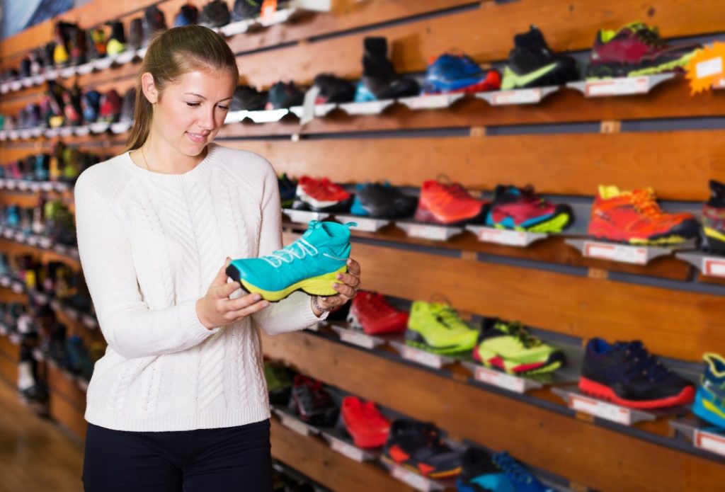 אישה בוחרת נעליים בקיר נעלי ריצה בחנות